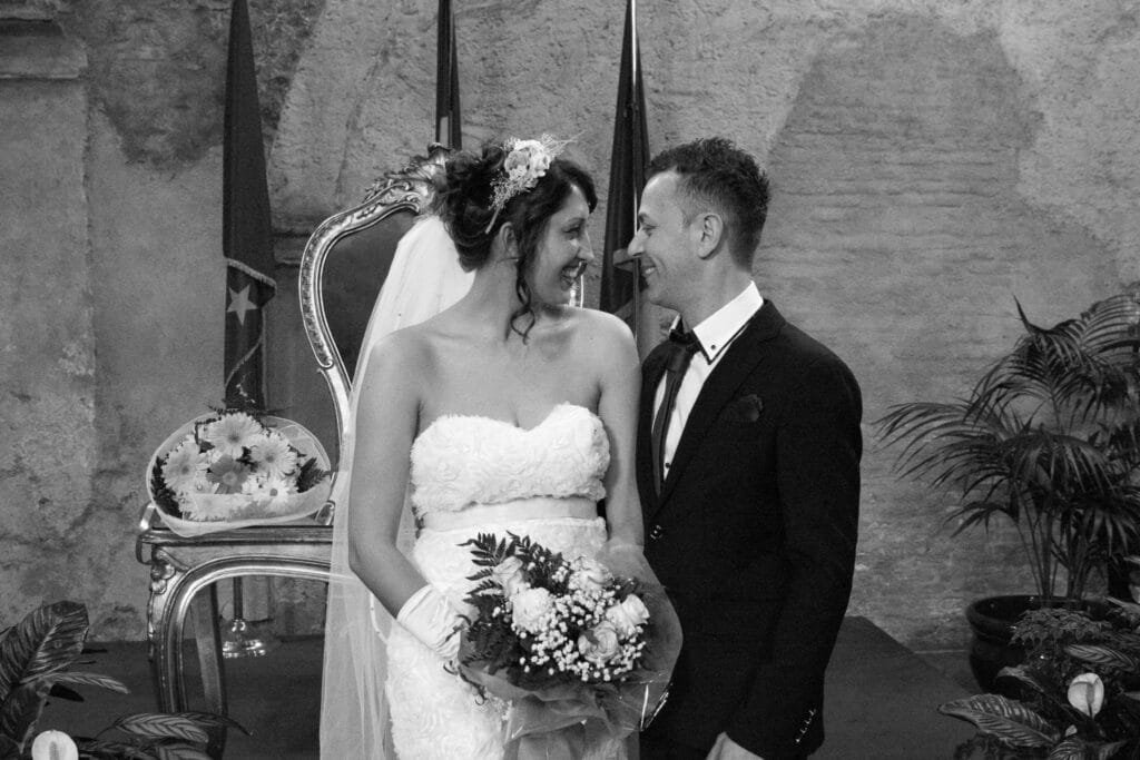 Cuplul zâmbind în timpul ceremoniei civile la Santa Maria in Tempulo, fotografie elegantă în alb-negru